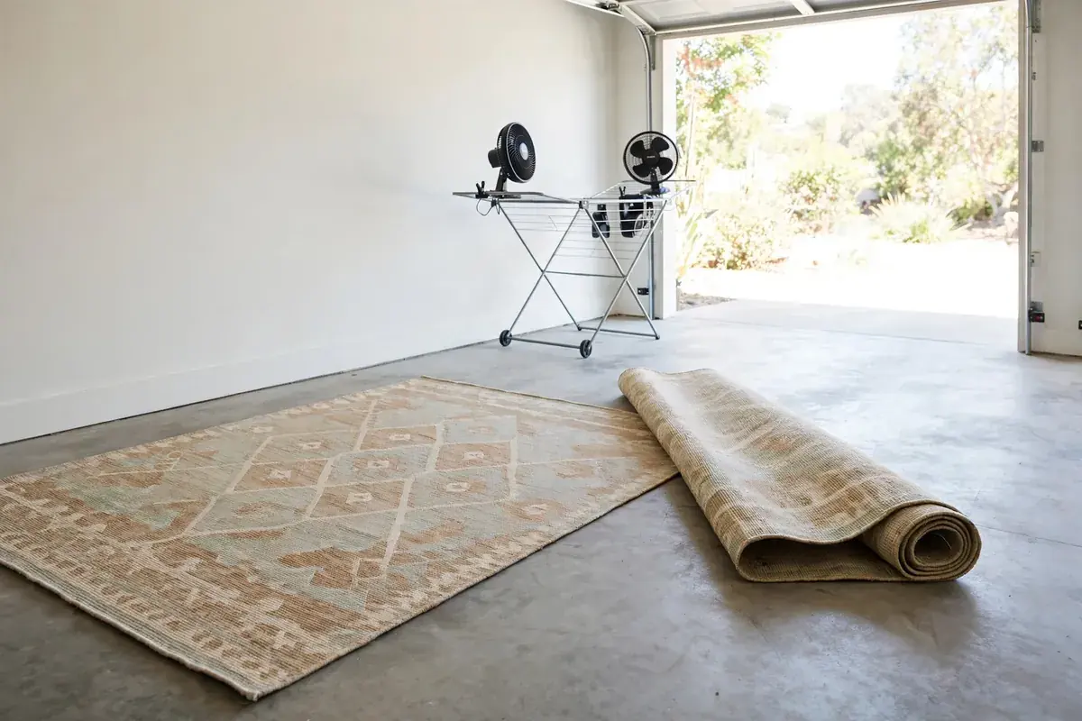 Area rugs laid flat and rolled on a clean floor beside drying fans
