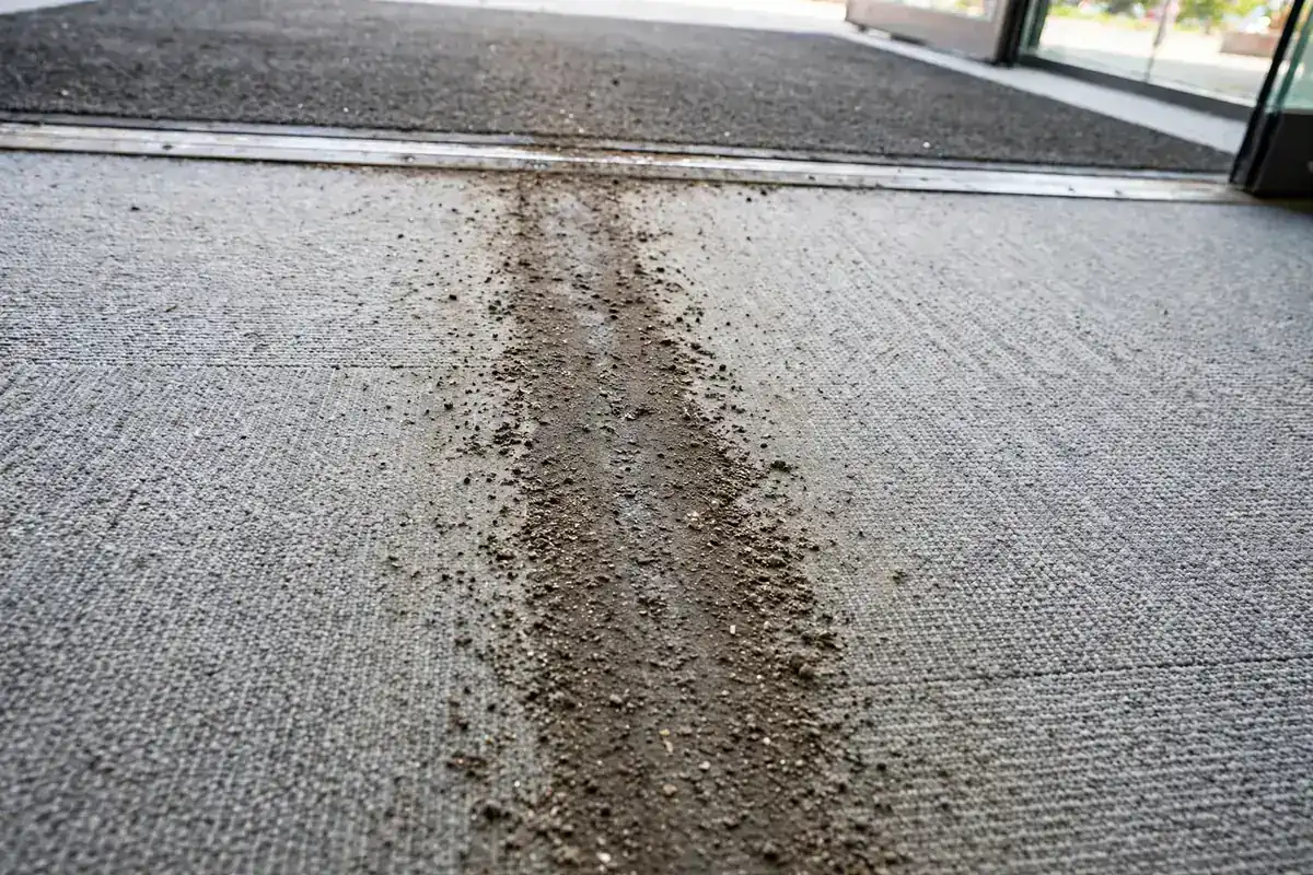 Gray carpet tile with a worn lane of grit leading from an office entrance