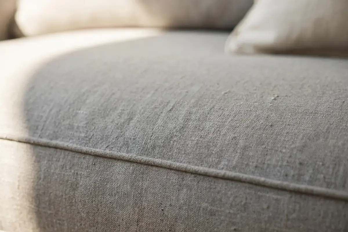 Gray fabric sofa cushion showing the woven texture and piped seam